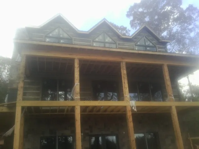Dormers and porch framing on a large log home under construction — Roof Coating work by our crew in Friendsville