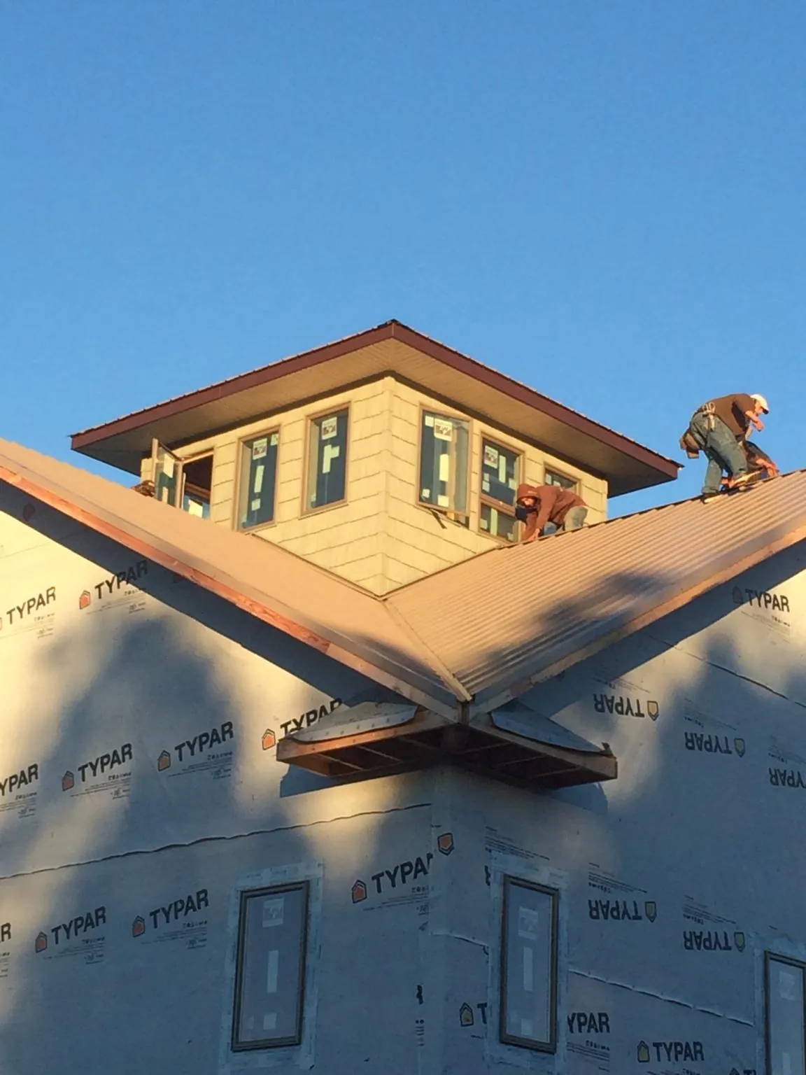 Roofers working around a rooftop cupola on a new metal roof at sunset — Roof Waterproofing in Friendsville by Roofing Brothers